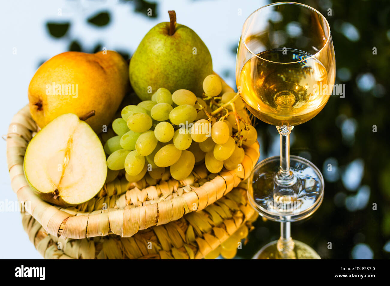 ripe juicy appetizing grape, pears and glass of wine on mirror background Stock Photo