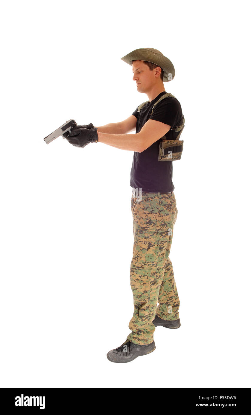 A soldier in camouflage pants, hat and black t-shirt aiming his hand gun isolated on white background. Stock Photo