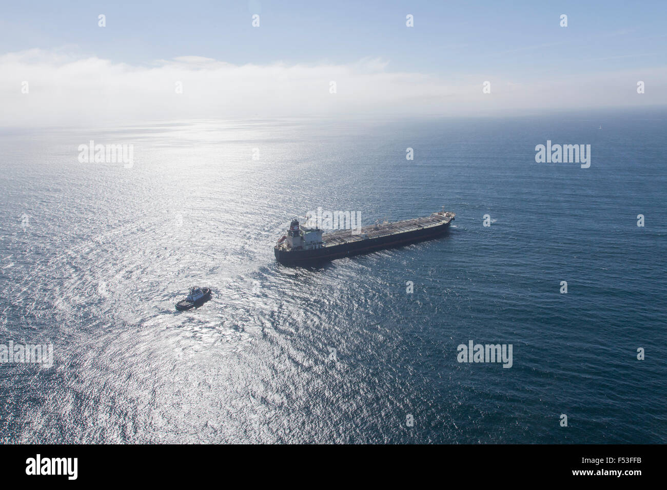 oil tanker freighter at sea with tug boat assist Stock Photo