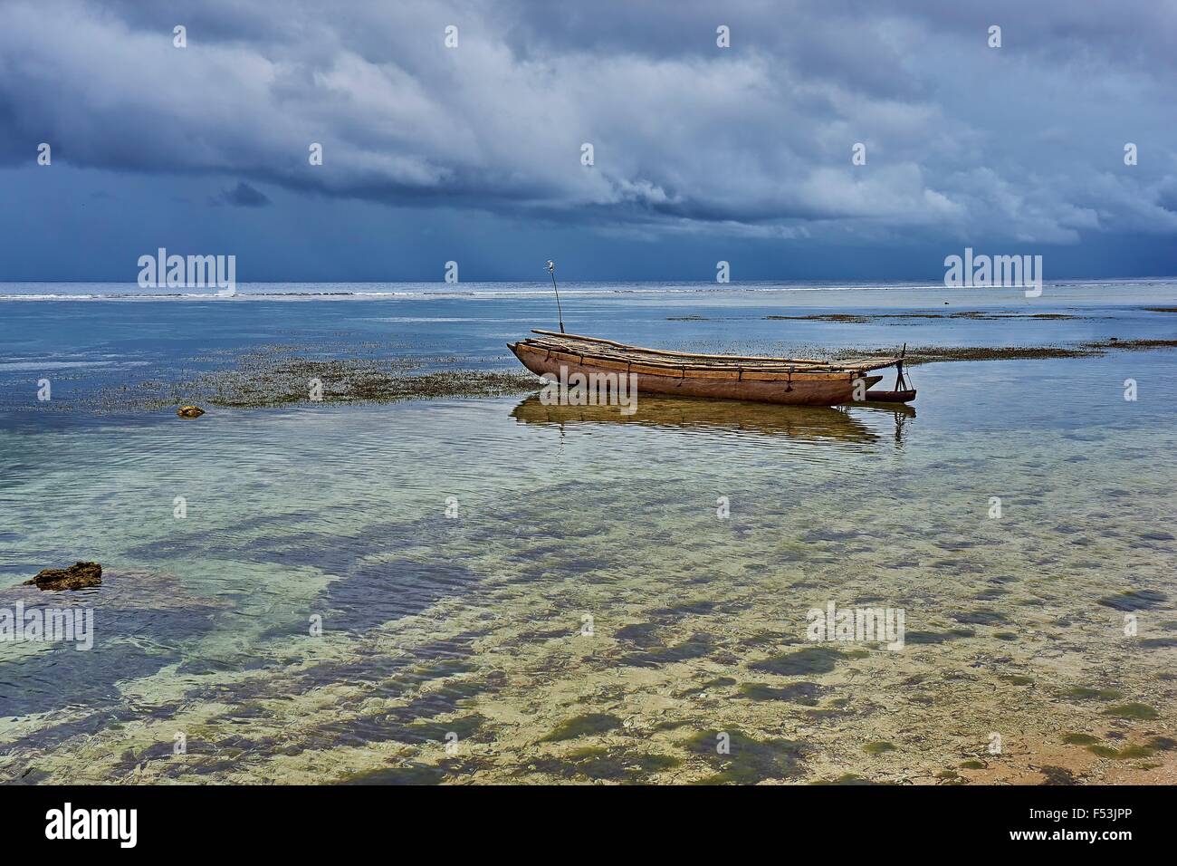 Kiriwina Island Outrigger Canoe in shallow waters near small Tropical Island Stock Photo