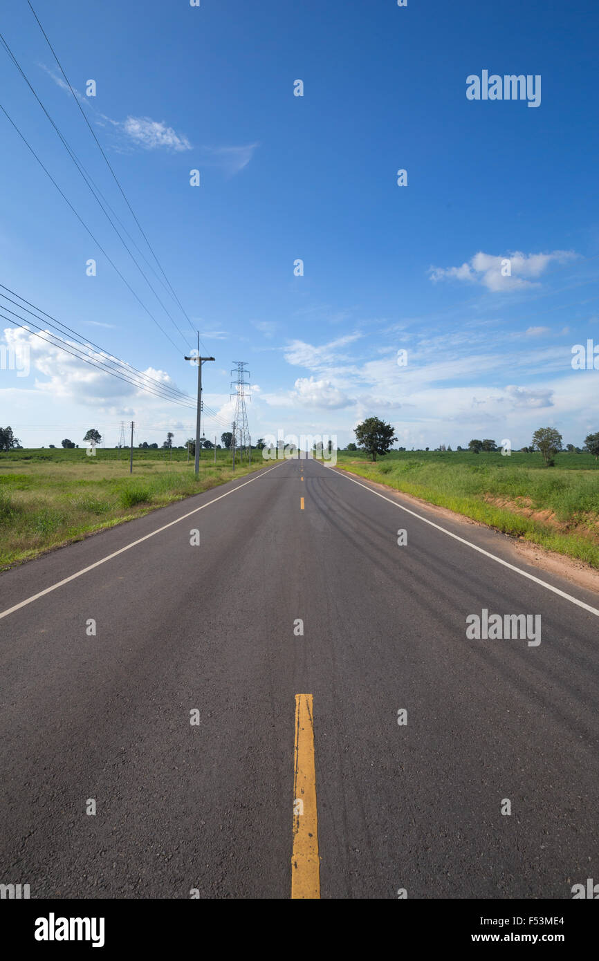 asphalt road through the green field with blue sky Stock Photo