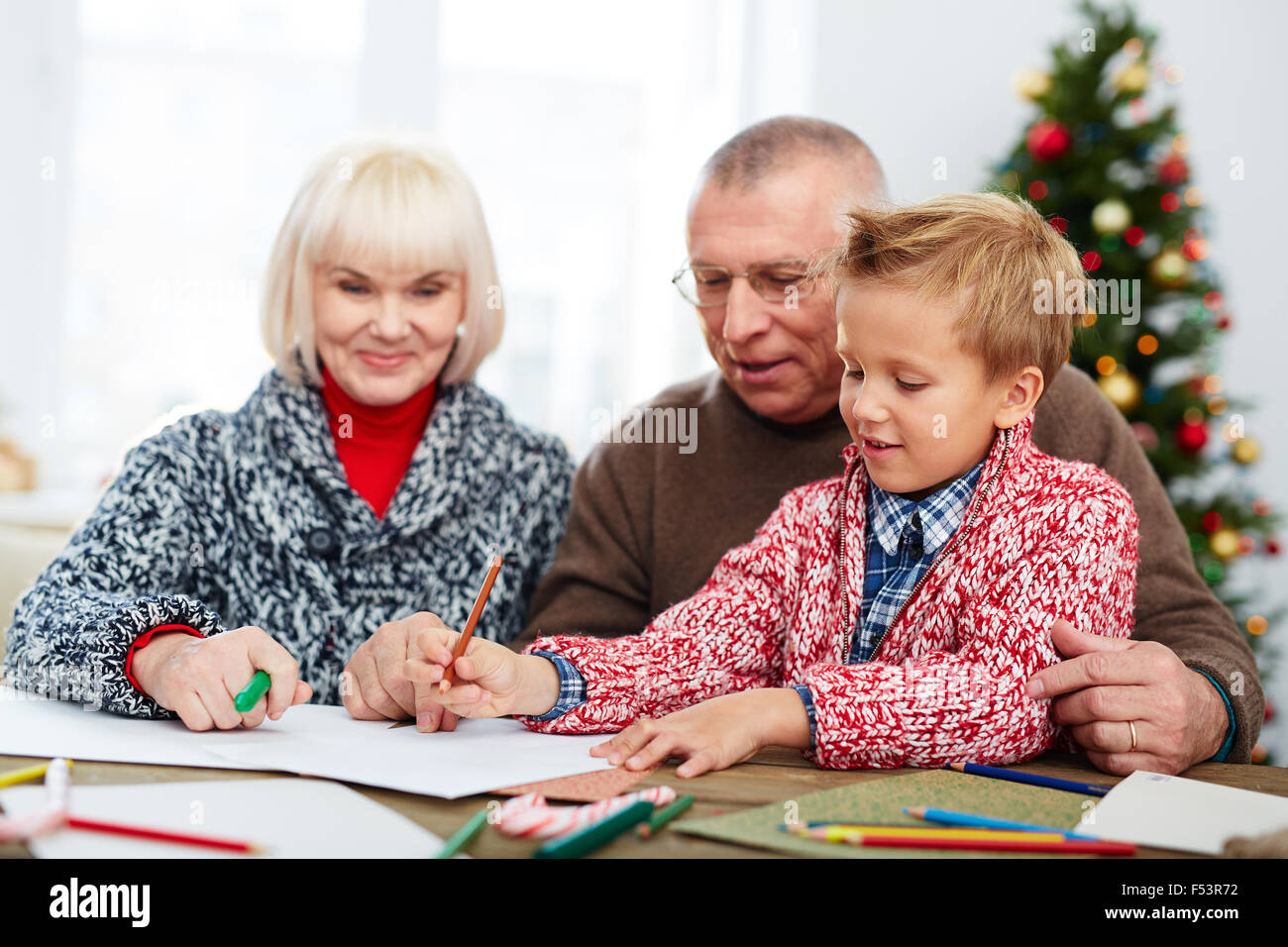 Boy writing a letter to Santa with his grandparents Stock Photo