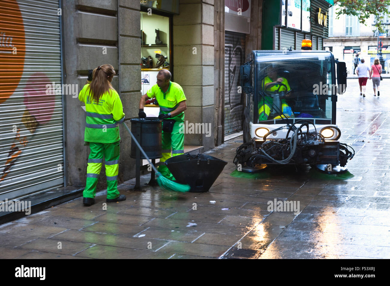 Street cleaners emptying litter bin & sweeping street in Barcelona