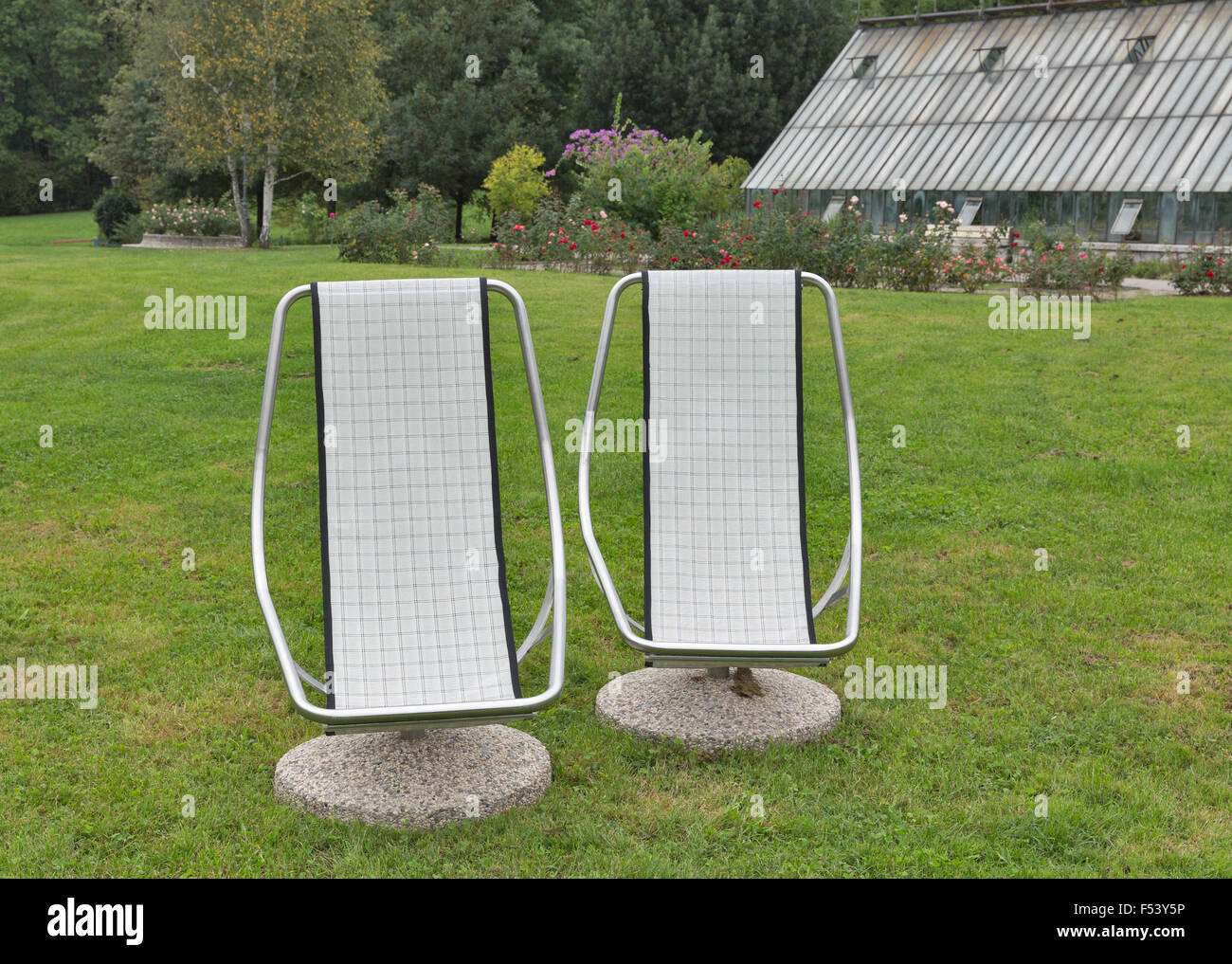 two stationary chairs for outdoor recreation closeup in front of greenhouse Stock Photo