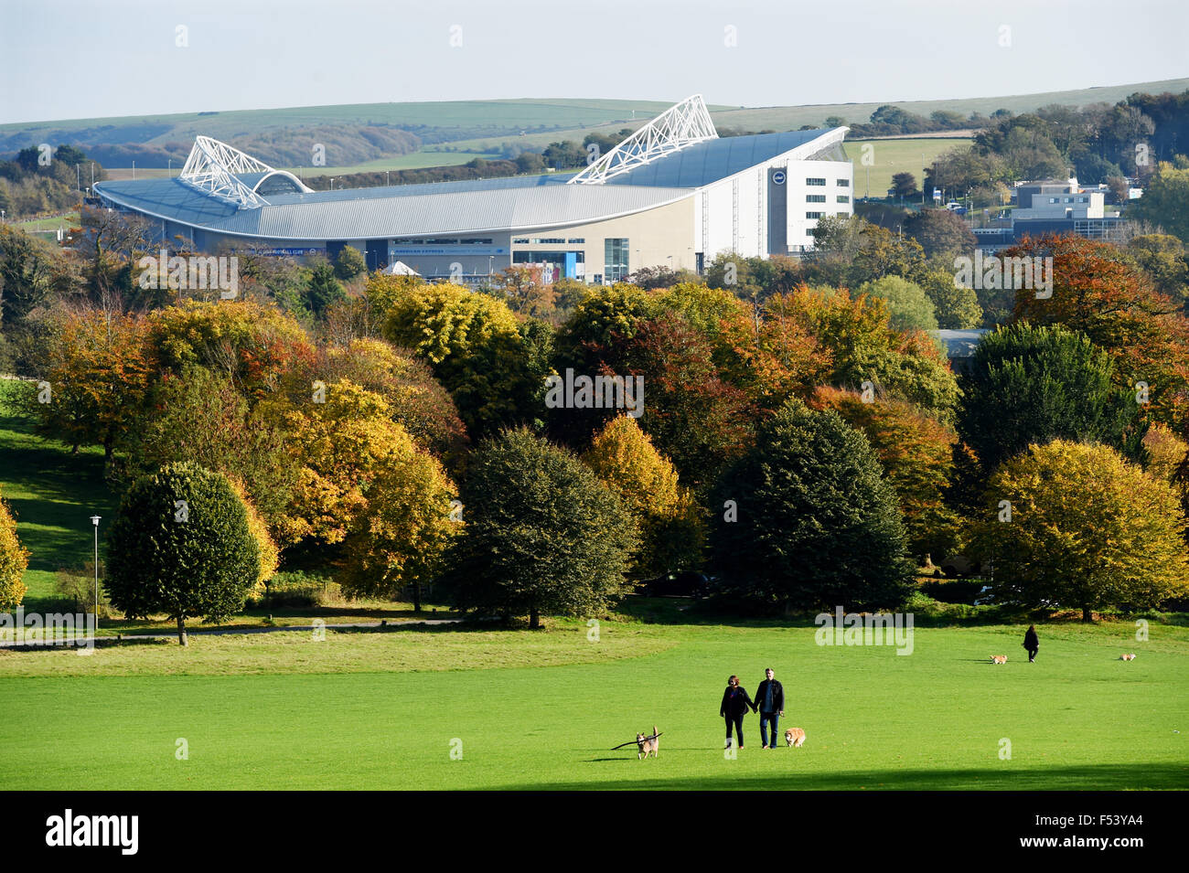 Brighton, Sussex, UK. 27th October, 2015. People out walking as they enjoy the beautiful weather and Autumn colours in Stanmer Park Brighton with temperatures reaching as high as 20 degrees in the south today . Behind the Brighton and Hove Albion football club American Express Community Stadium rises above the trees Credit:  Simon Dack/Alamy Live News Stock Photo