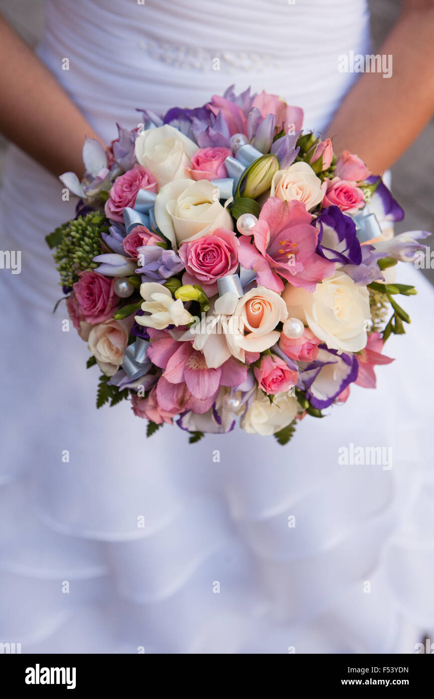 round bouquet with white roses, purple and pink freesia and pearls in the  hands of the bride Stock Photo - Alamy