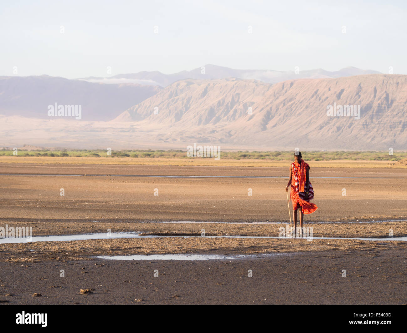 Maasai warrior wearing traditional red clothes in the dried part of Lake Natron in the North of Tanzania, Africa. Stock Photo