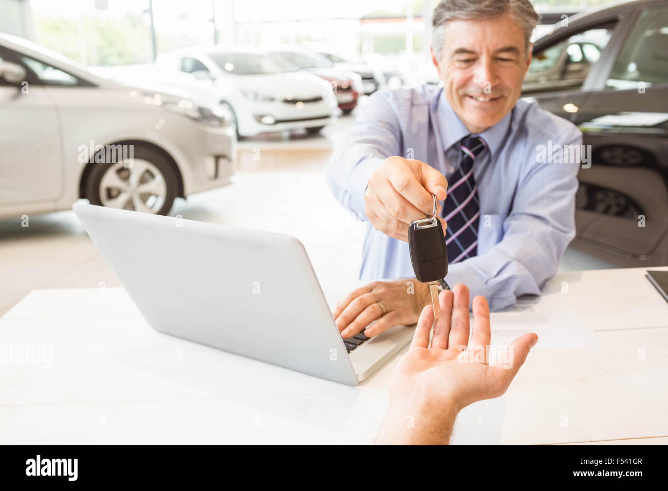 Smiling salesman holding a customer car key Stock Photo - Alamy