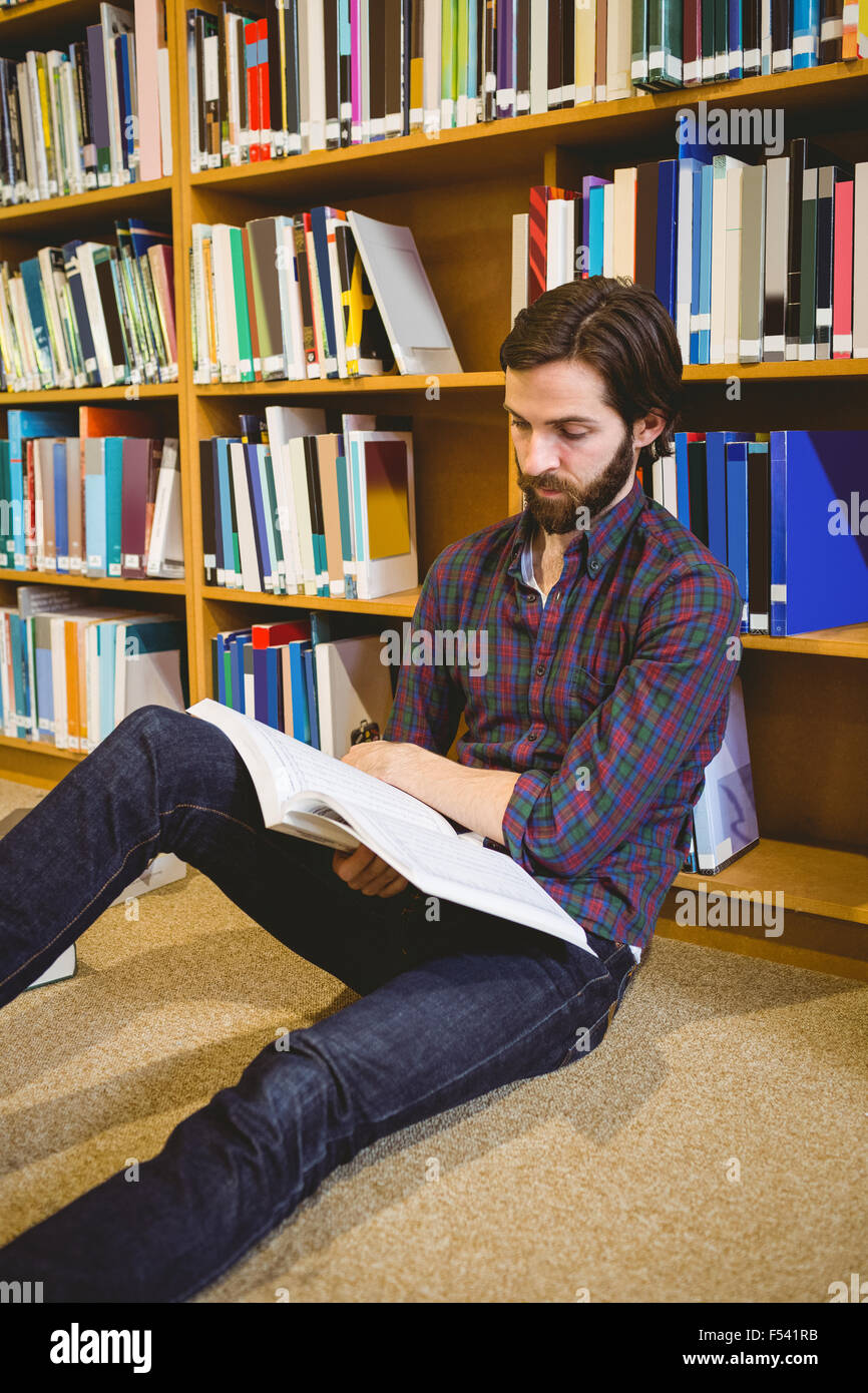 Student reading book in library on floor Stock Photo