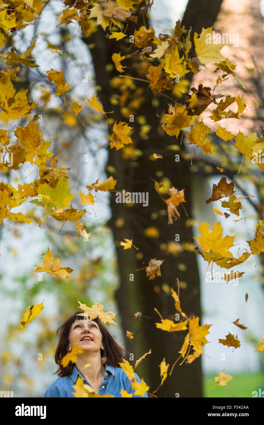 Woman looks up at the falling leaves in the autumn park Stock Photo - Alamy