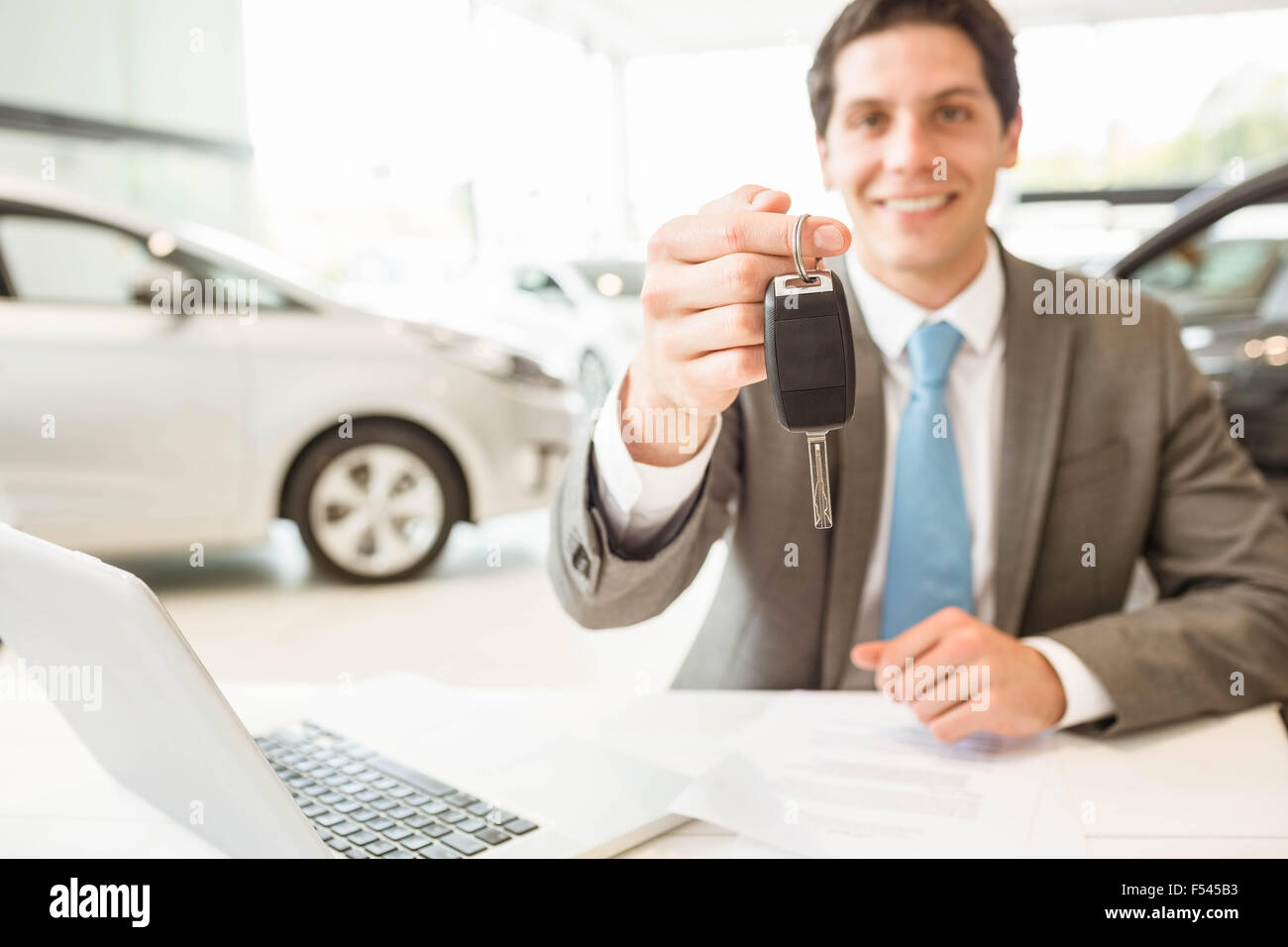 Smiling salesman holding a customer car key Stock Photo - Alamy