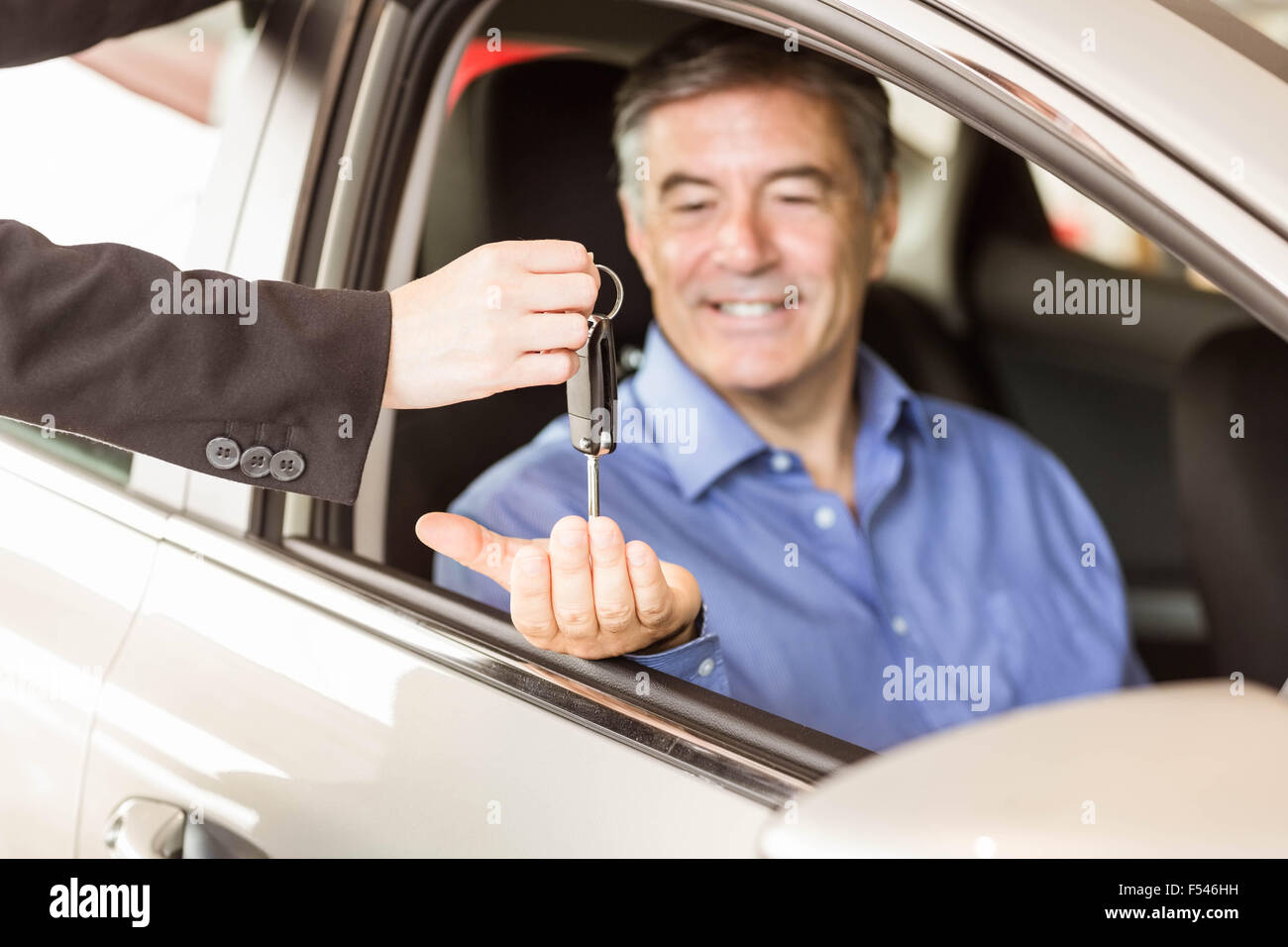 Salesman giving keys to a smiling businessman Stock Photo - Alamy