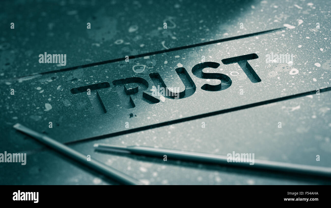 Word trust engraved in black stone with tools and blur effect. Concept image for illustration of strong relationship or partners Stock Photo