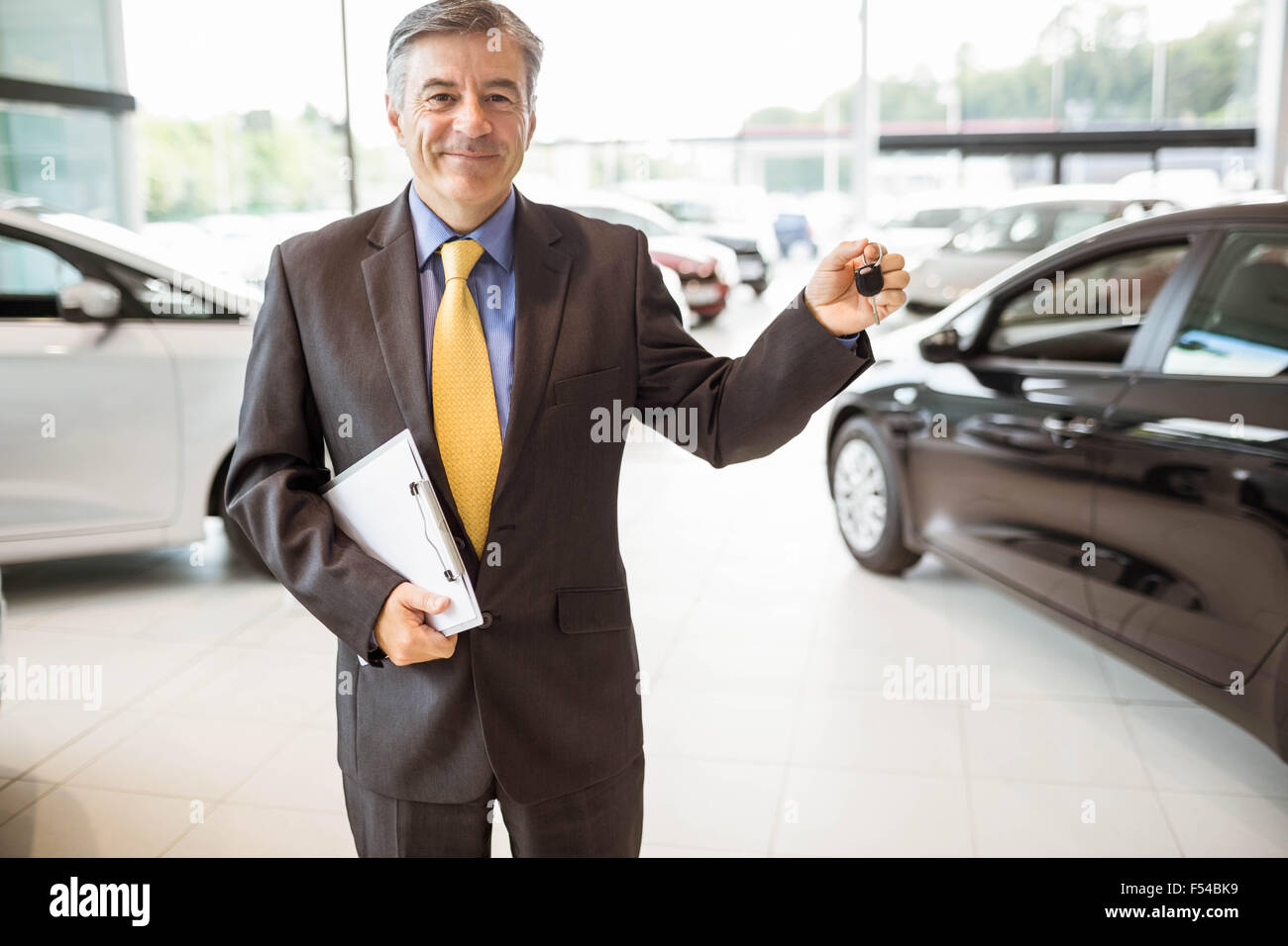 Smiling salesman holding a customer car key Stock Photo - Alamy