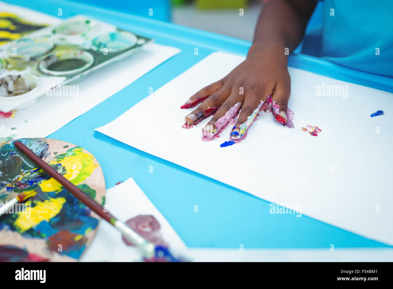 Happy kid enjoying painting with his hands Stock Photo