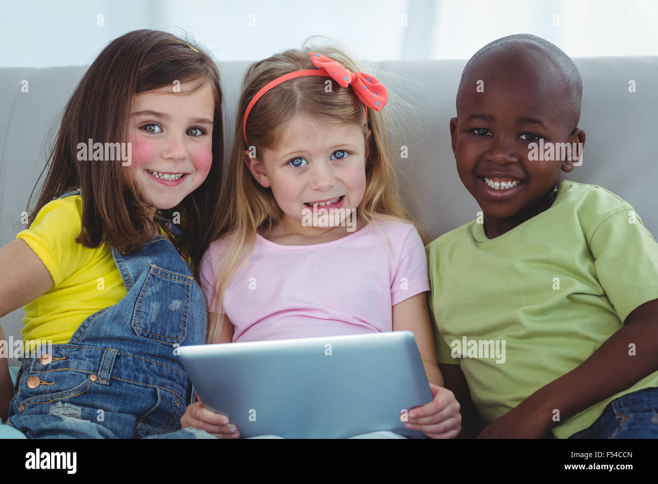 Happy kids sitting together with a tablet Stock Photo - Alamy