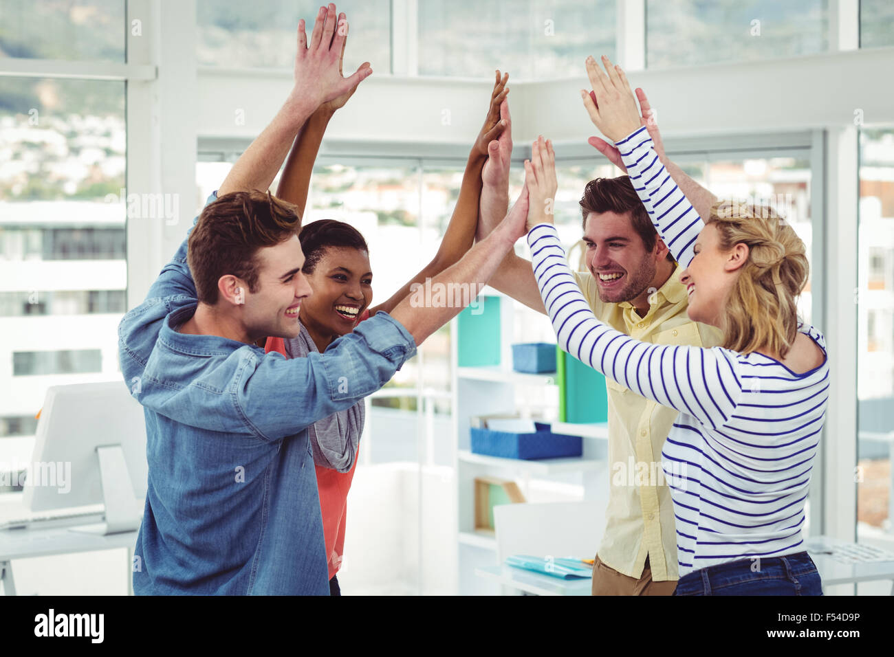 Happy creative team giving high fives to each other Stock Photo