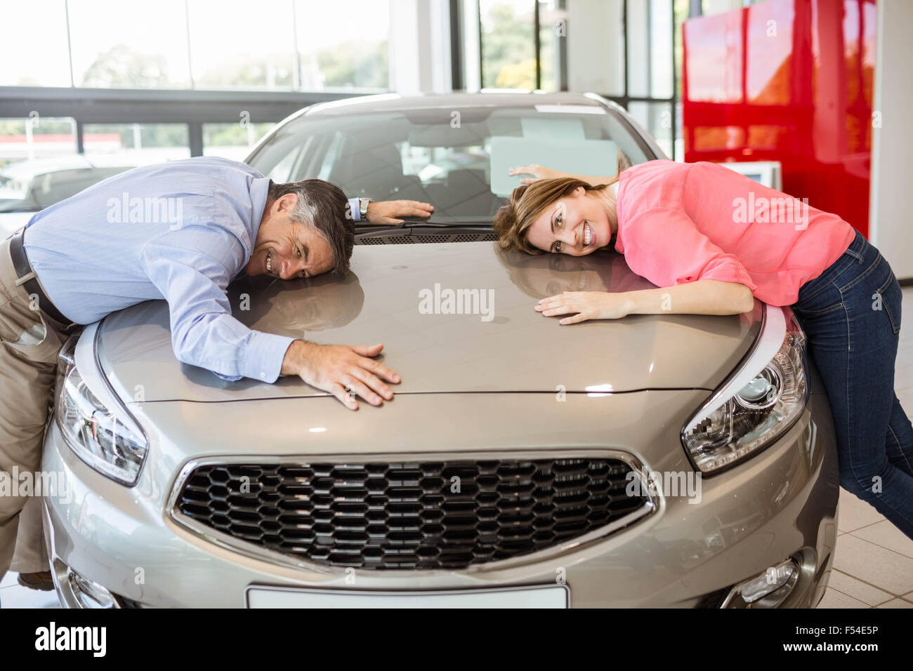 Casual smiling couple hugging their new car Stock Photo