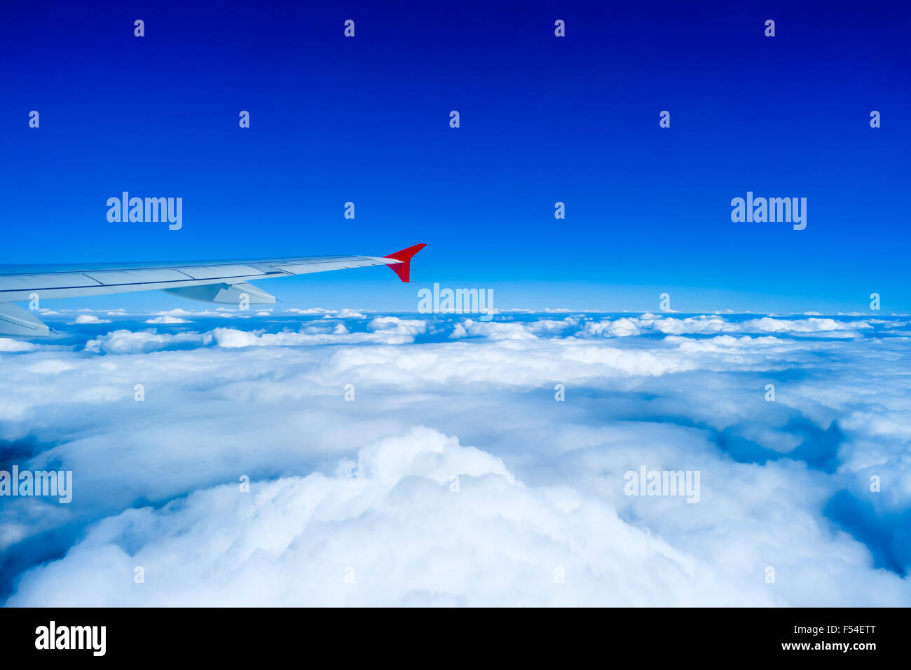 Wing of airplane flying in sky above clouds Stock Photo