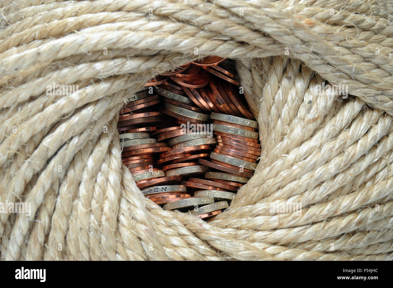 BRITISH COINS WRAPPED IN ROPE RE SAVINGS INCOMES PENSIONS RETIREMENT OLD AGE ONE POUND INVESTMENTS BANKS WAGES HOUSEHOLD CASH UK Stock Photo