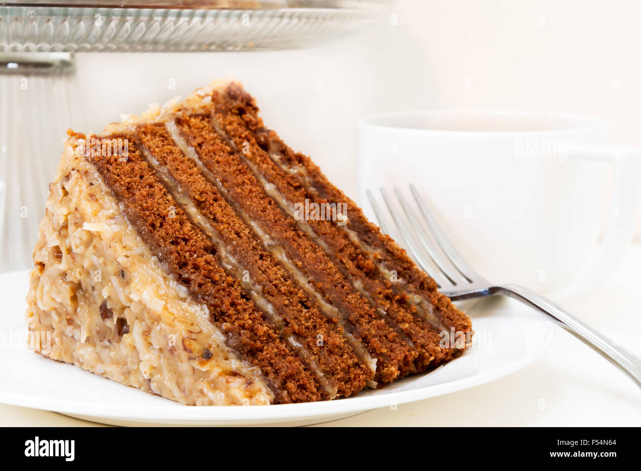 Slice of german chocolate cake closeup with cup of coffee.  Isolated on white background. Stock Photo