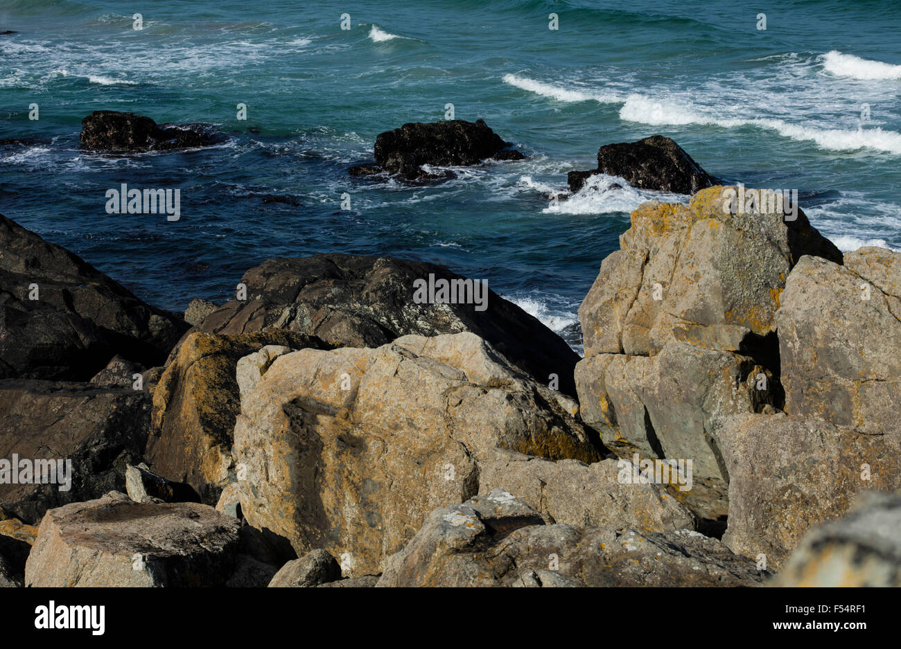 Rocks by the coast with a stormy sea with white waves and crests in ...