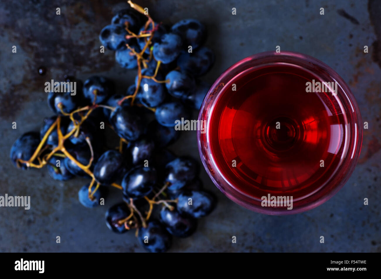 Glass of young red wine with grapes on top Stock Photo