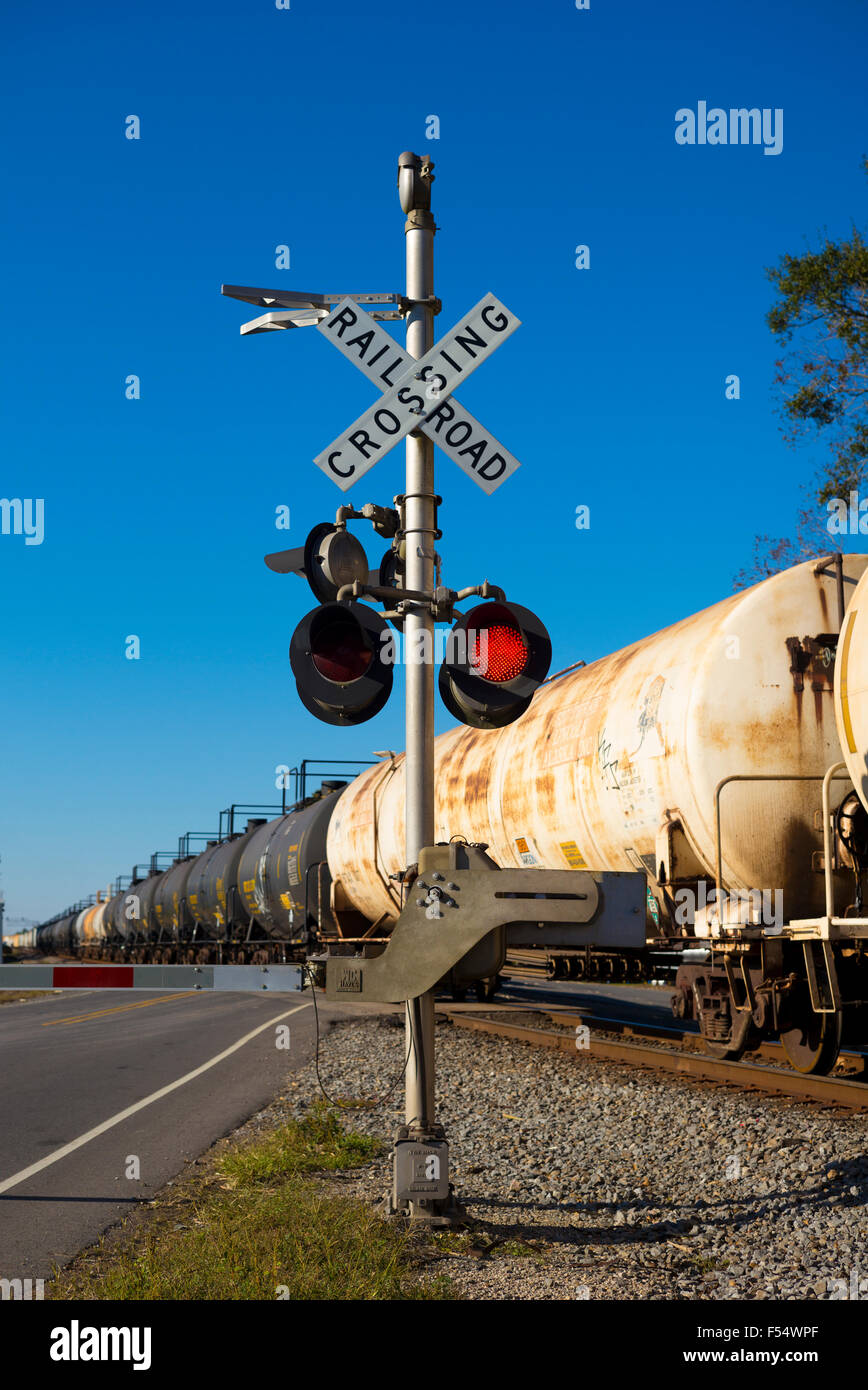 Freight train of tankers and carriages at railroad crossing with red traffic lights in Louisiana, USA Stock Photo
