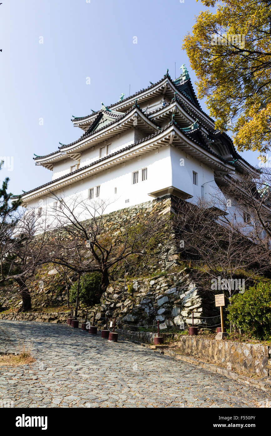 Japan, Wakayama castle. Path by stone base of keep, tenshu towering over viewer, with corner murder hole, stone dropping chute. Stock Photo