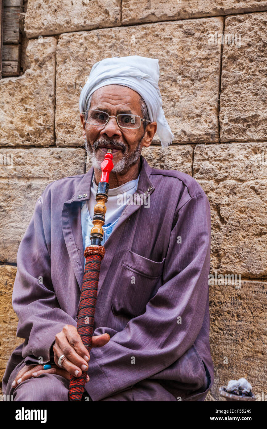 Arab man smokes a traditional Arabian shisha in the Khan el-Khalili souk in Cairo. Stock Photo