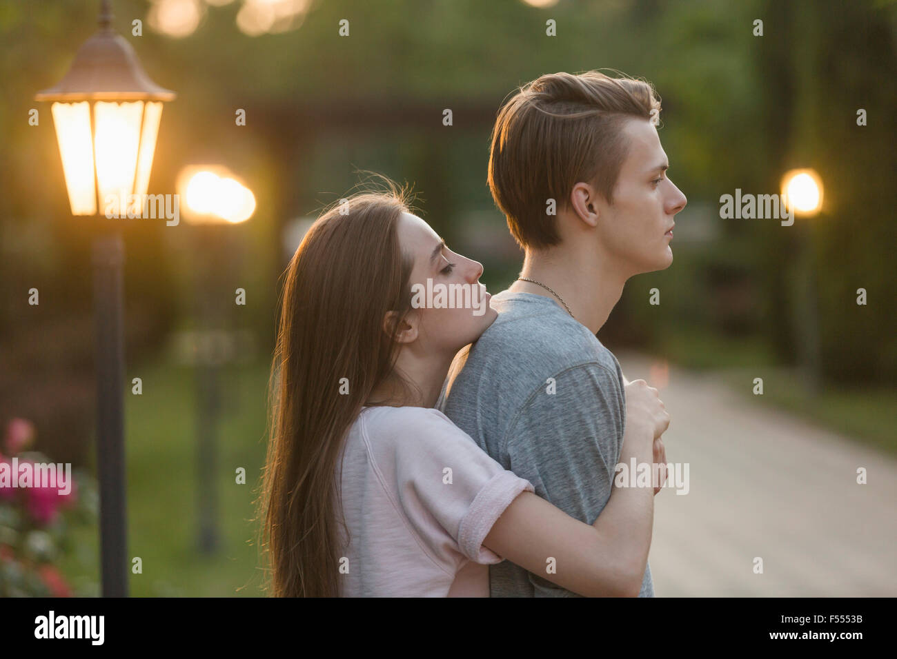Side view of young woman embracing boyfriend at park Stock Photo