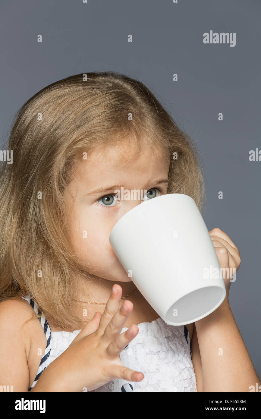 Cute girl drinking coffee against gray background Stock Photo