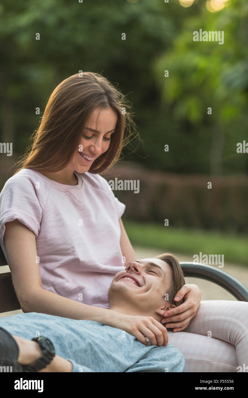 Happy young man lying on woman's lap at park Stock Photo