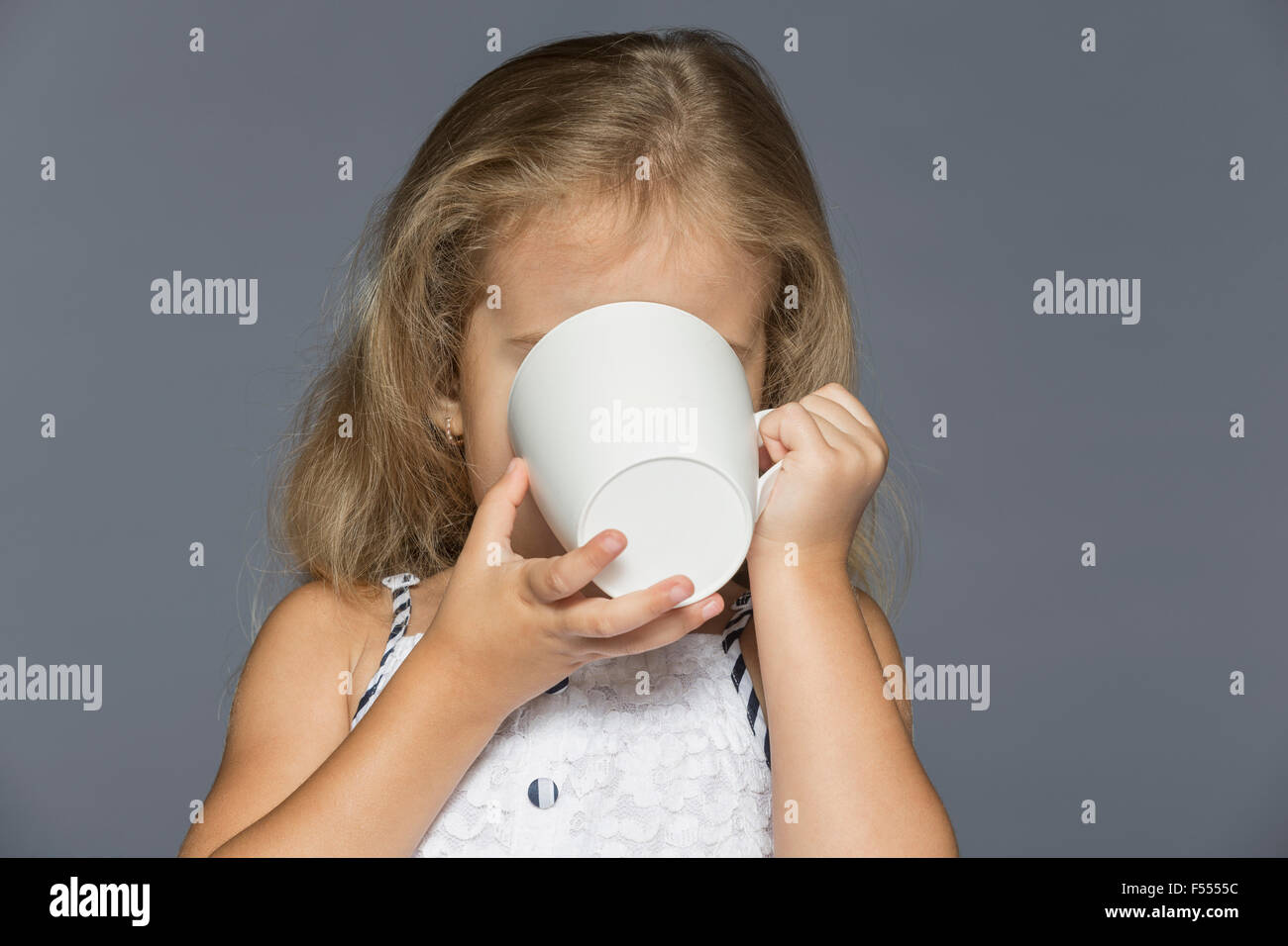 Girl drinking coffee against gray background Stock Photo