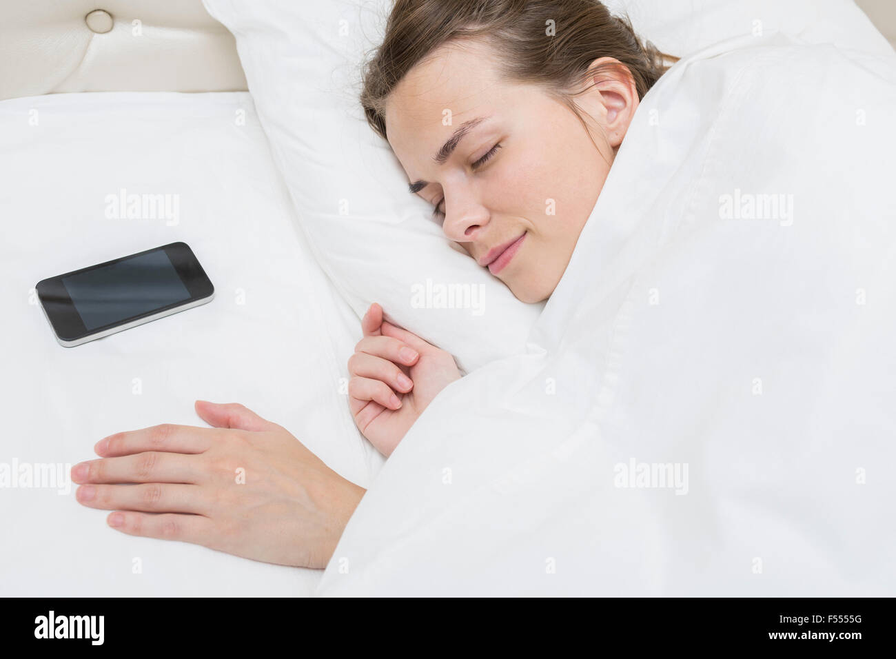 High angle view of beautiful woman sleeping with smart phone on pillow in bed Stock Photo