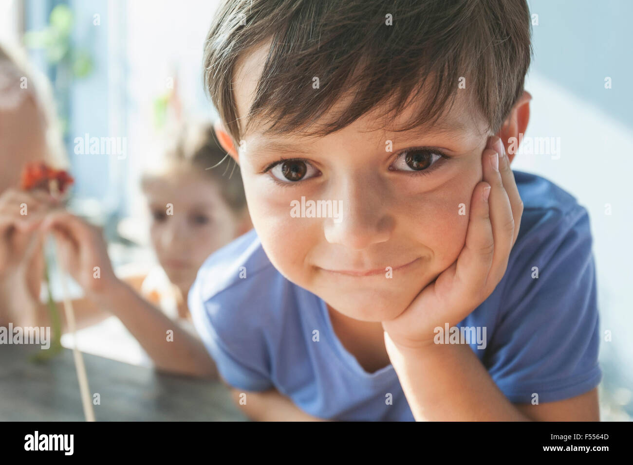 Close-up portrait of cute boy leaning on table at home Stock Photo