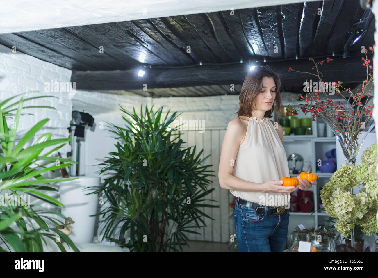 Female owner holding artificial pumpkins at decor shop Stock Photo