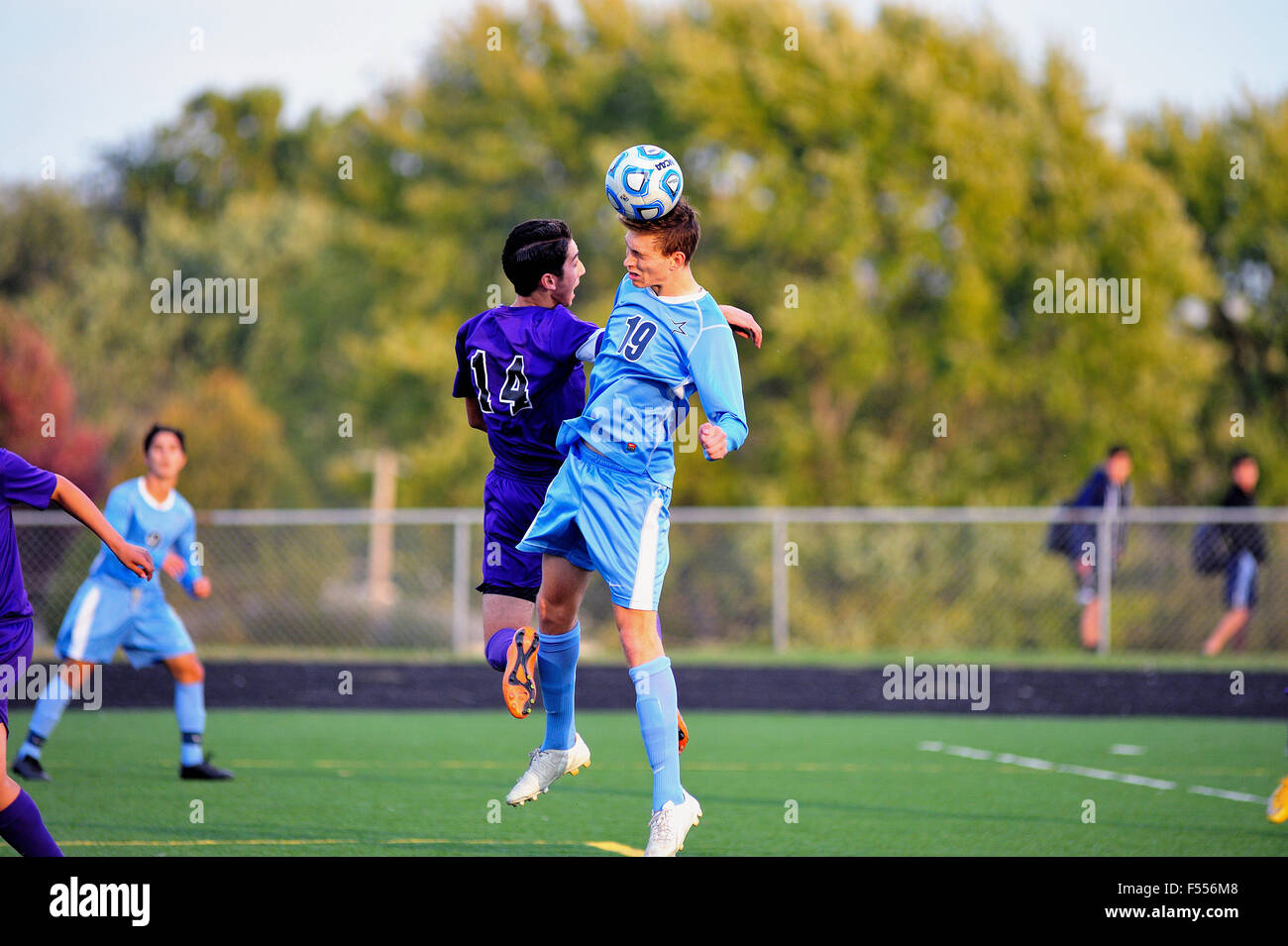 Players battle to execute a header during a high school soccer match. USA. Stock Photo