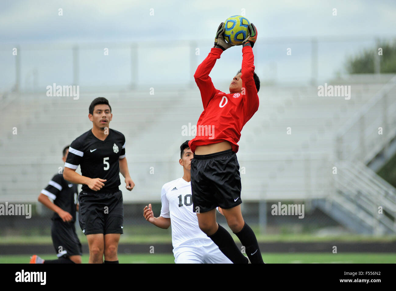 A high school keeper leaves the pitch to make a save on a shot that was destined  for an upper corner of the net. Stock Photo