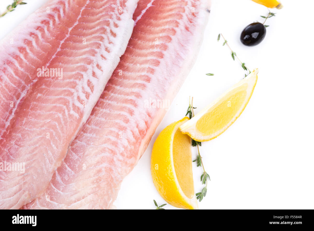uncooked raw fillet of pangasius with lemon and olive on white background Stock Photo
