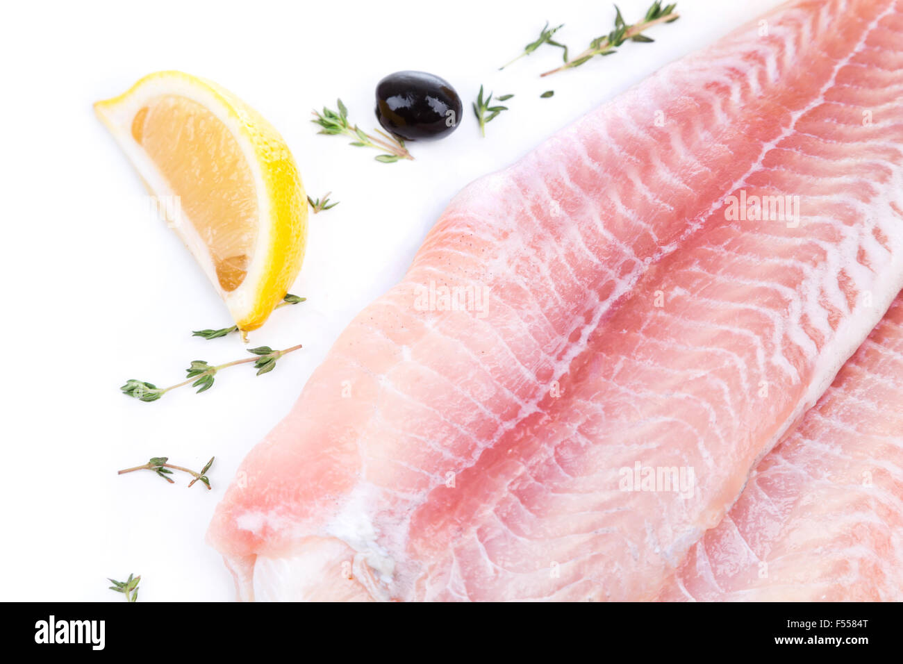 uncooked raw fillet of pangasius with lemon and olive on white background Stock Photo