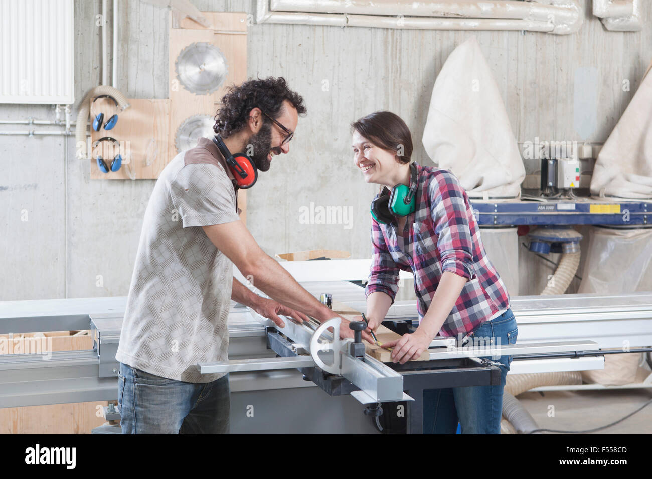 Side View Of Laughing Coworkers Using A Sliding Table Saw In Workshop Stock Photo Alamy