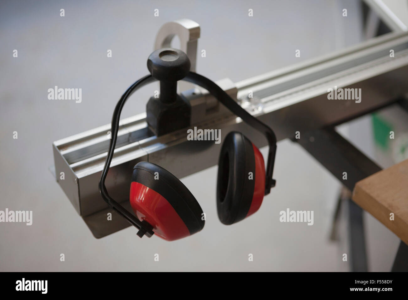 Ear protector hanging from sliding table saw in workshop Stock Photo