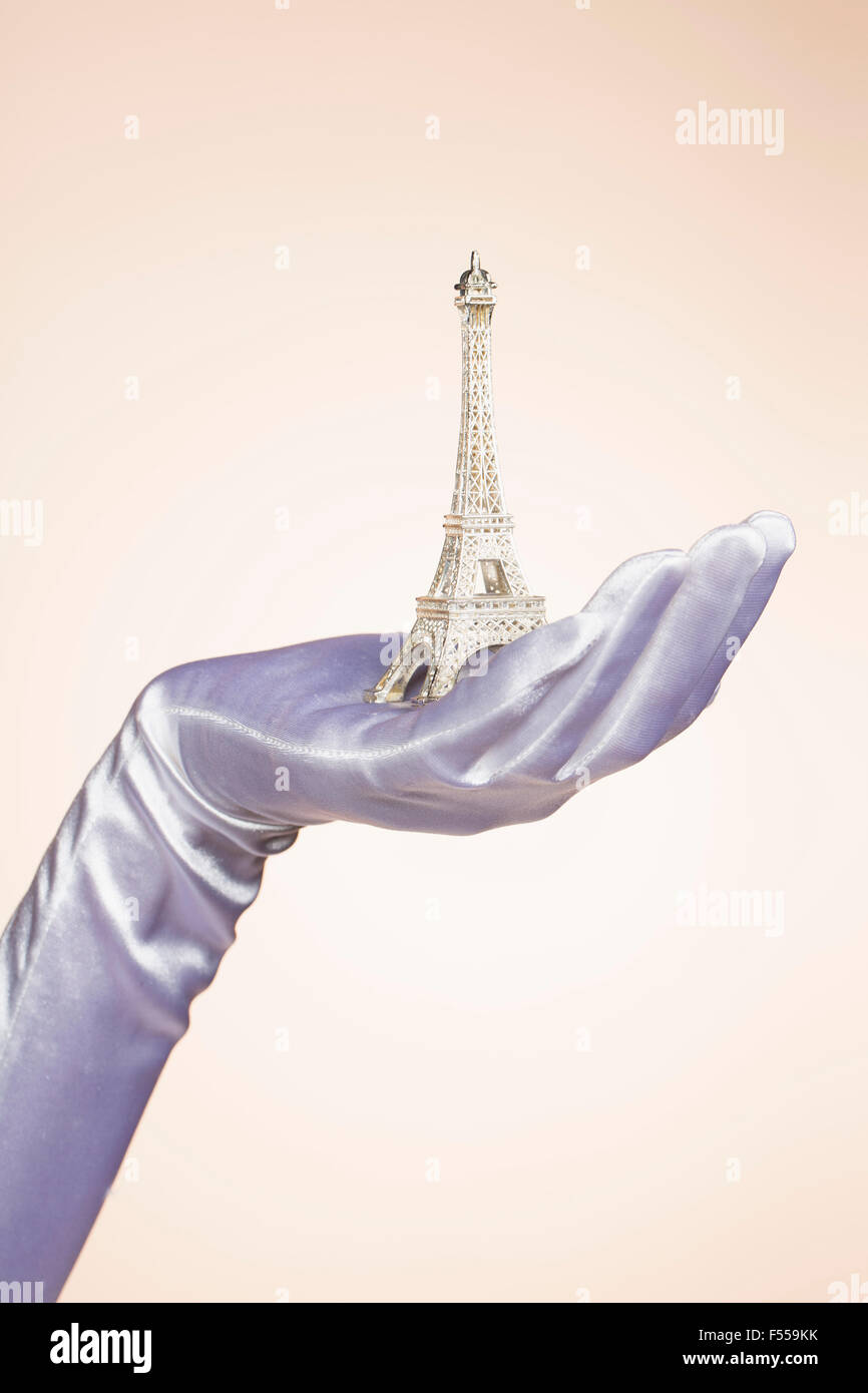 Cropped hand of bride holding Eiffel Tower model against colored background Stock Photo