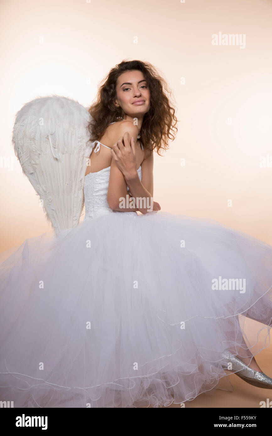 Portrait of smiling bride wearing angel wings against colored background Stock Photo