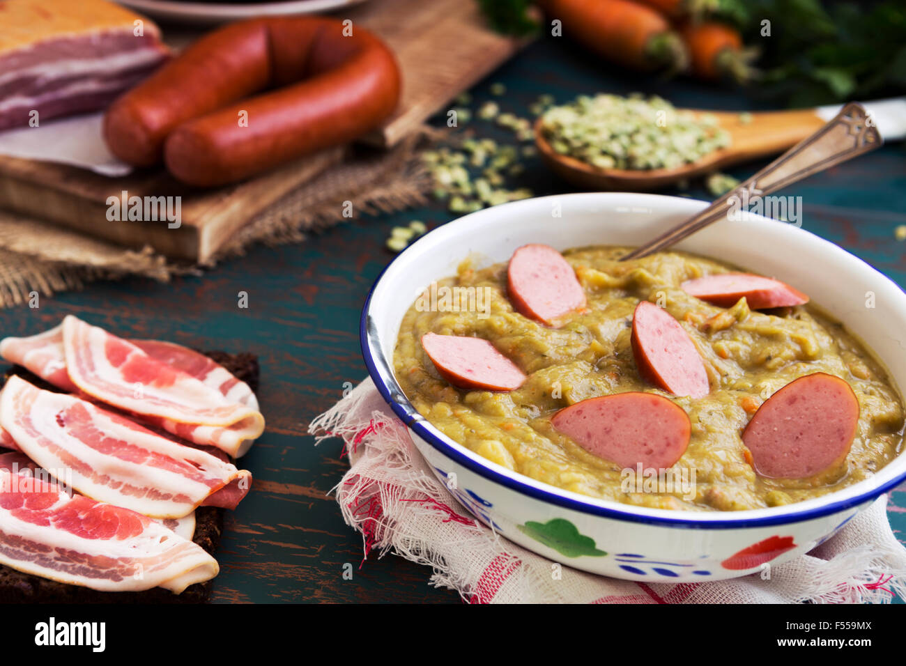 Hearty traditional Dutch pea soup with smoked sausage, rye bread and bacon. Or: 'erwtensoep met rookworst, roggebrood en spek'. Stock Photo