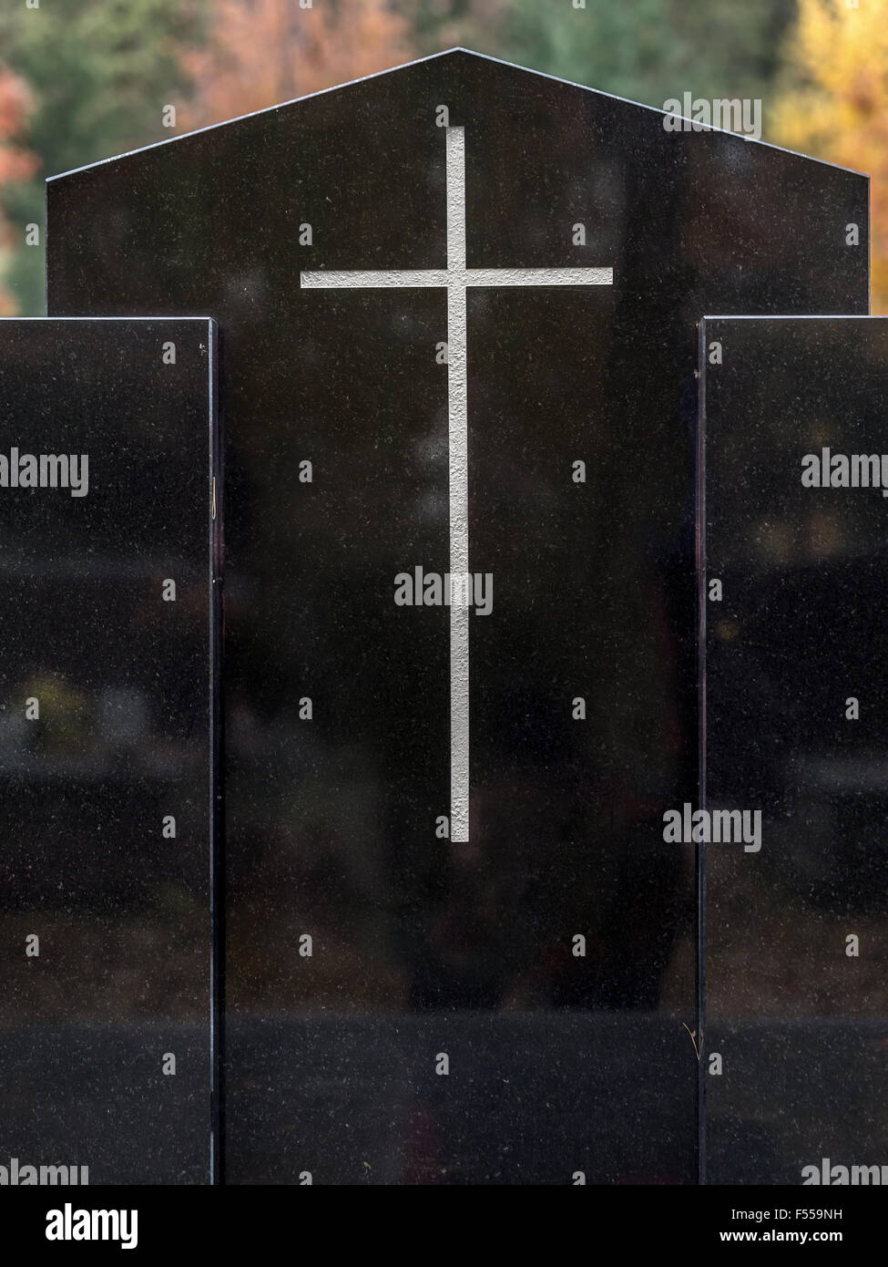 Closeup of black granite tombstone with white cross Stock Photo