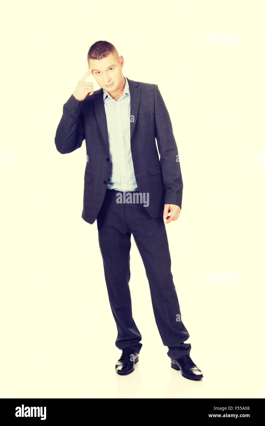 Businessman gesturing with finger against temple Stock Photo