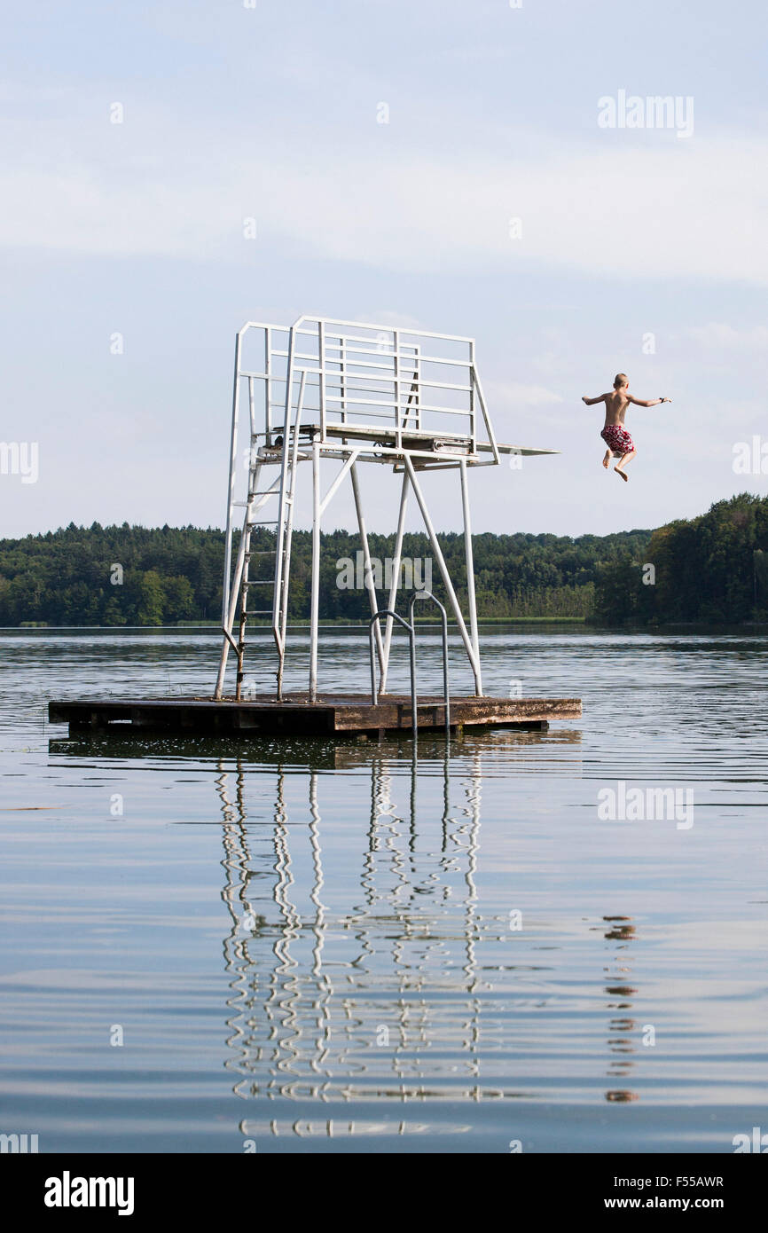 Rear view of boy jumping in lake against sky Stock Photo