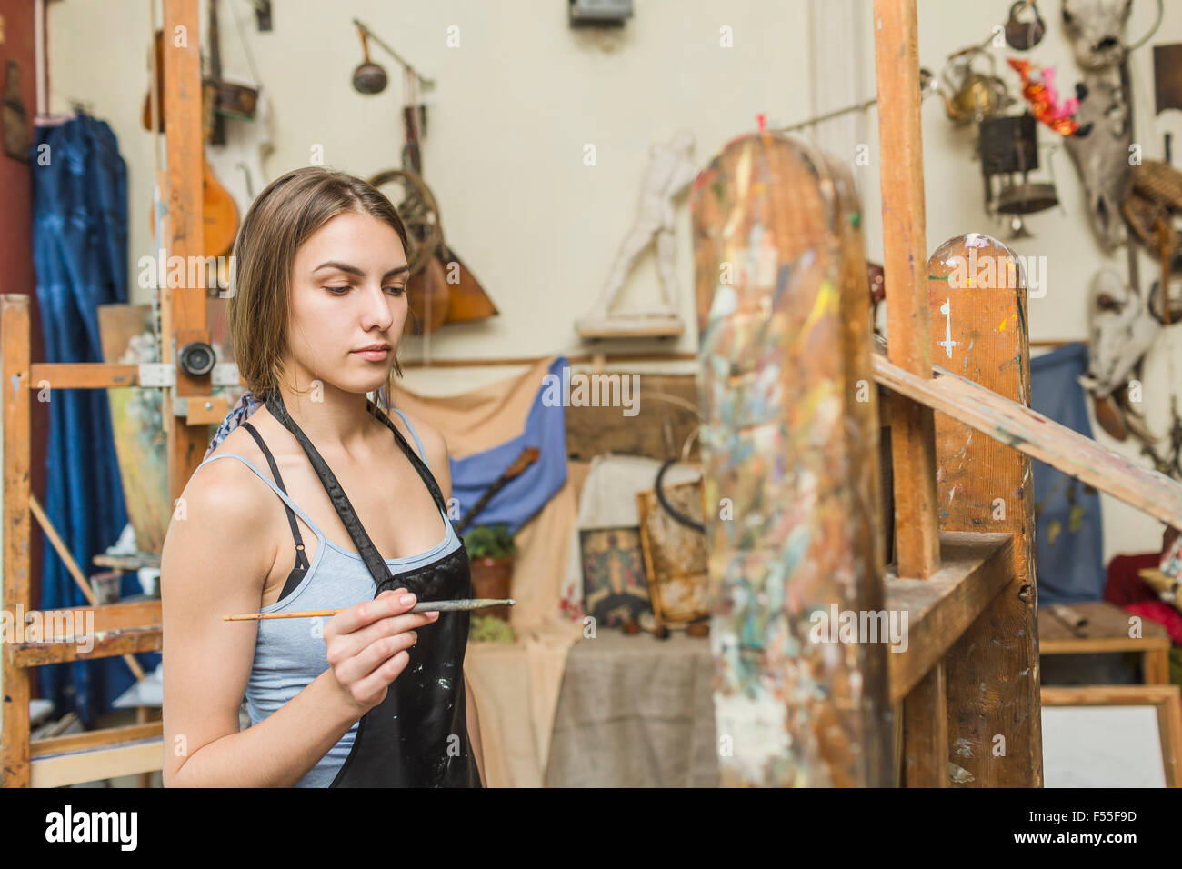 Female painter holding paintbrush and looking at easel at studio Stock Photo